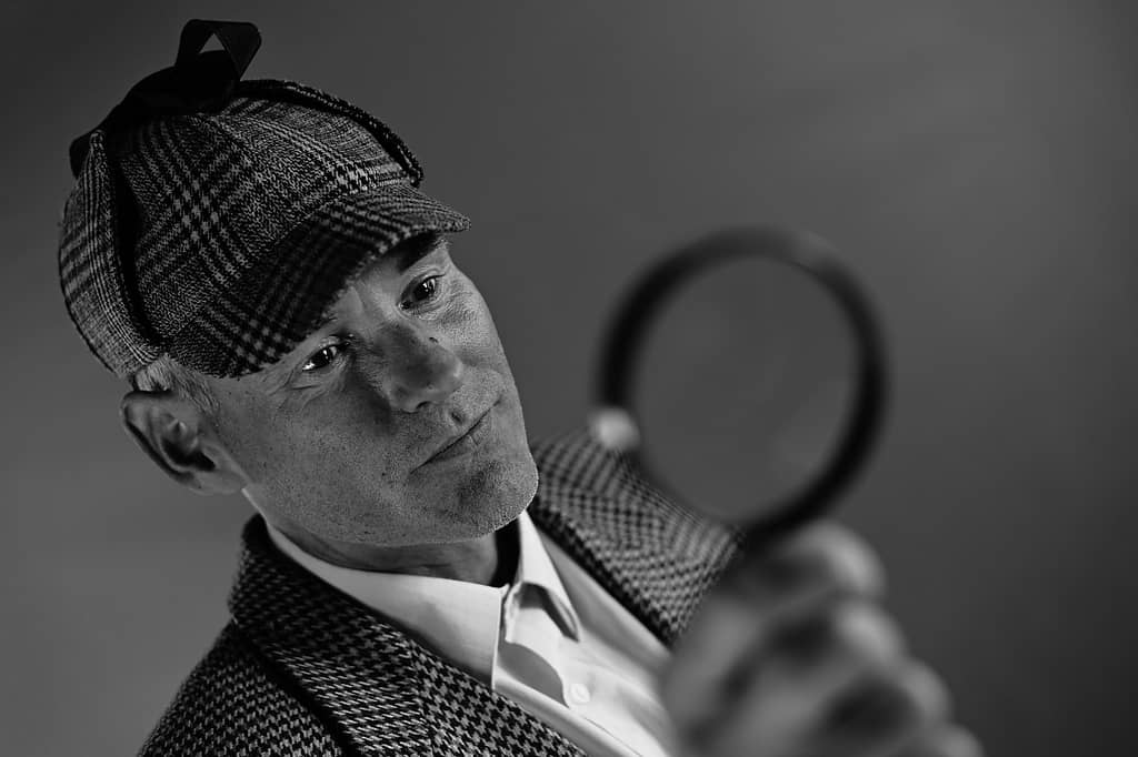 man in red and white checkered dress shirt wearing black fedora hat