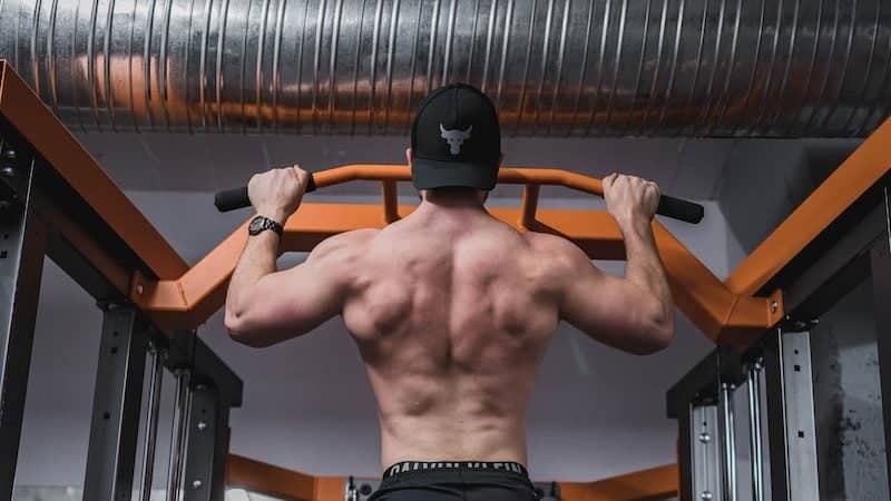 topless man in black pants and black nike shoes