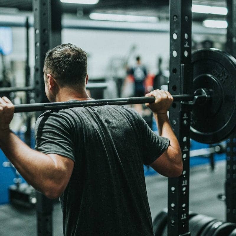 man in black t-shirt carrying barbell